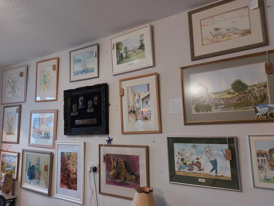 A wall of the shop hung with framed original watercolours by local artists, including a bronze relief titled Great Irish Writers