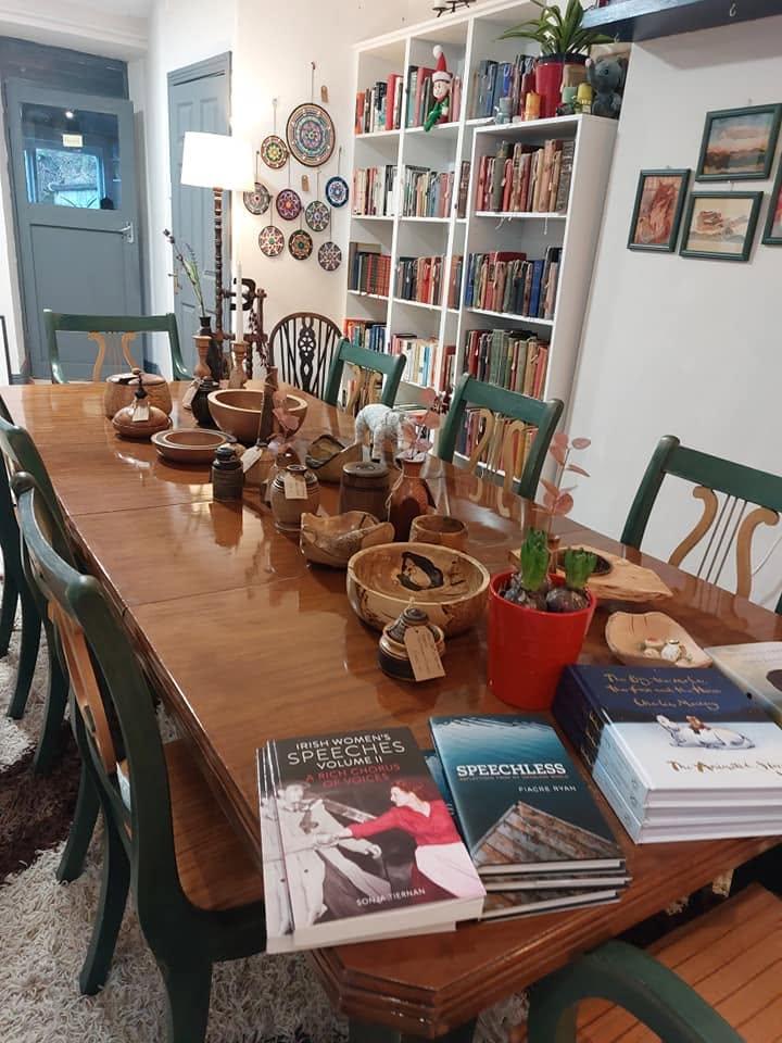 The big communal table at Sneem Book Shop, laden with hand-turned wooden bowls and new Irish titles, with bookshelves behind